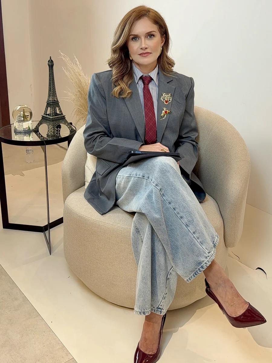 Mulher em traje social completo — blazer, gravata e scarpin — pronta para o dia.
